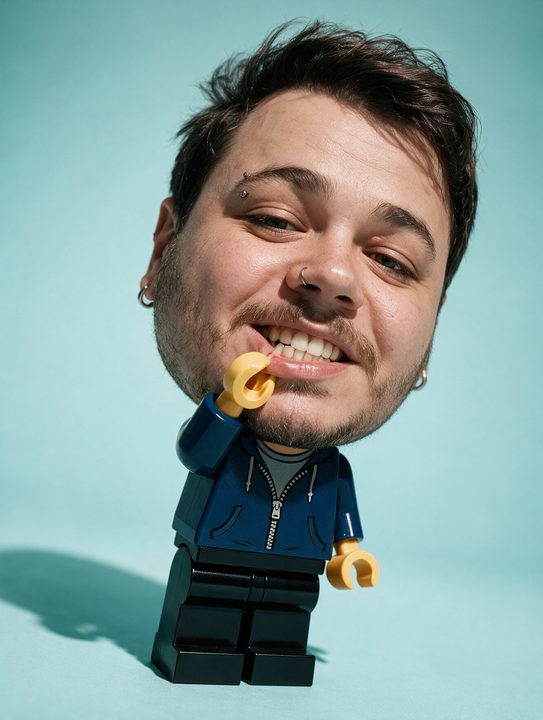 Cabeça real de João Felipe sobre um corpo de boneco de plástico segurando uma flor, em fundo azul claro