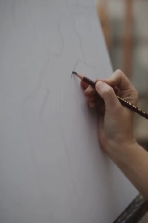 Mão segurando um pincel fino diante de uma tela em branco